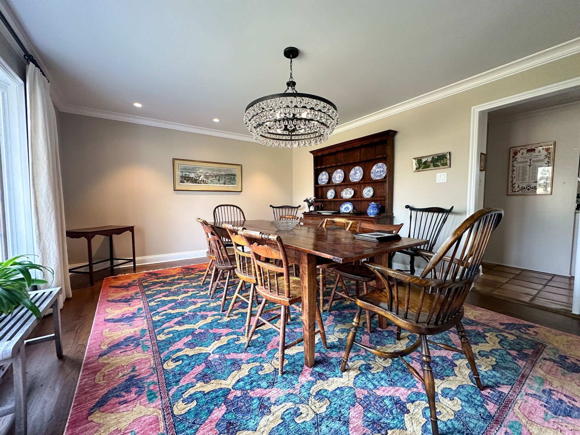 A dining room with a long table and chairs and a rug.