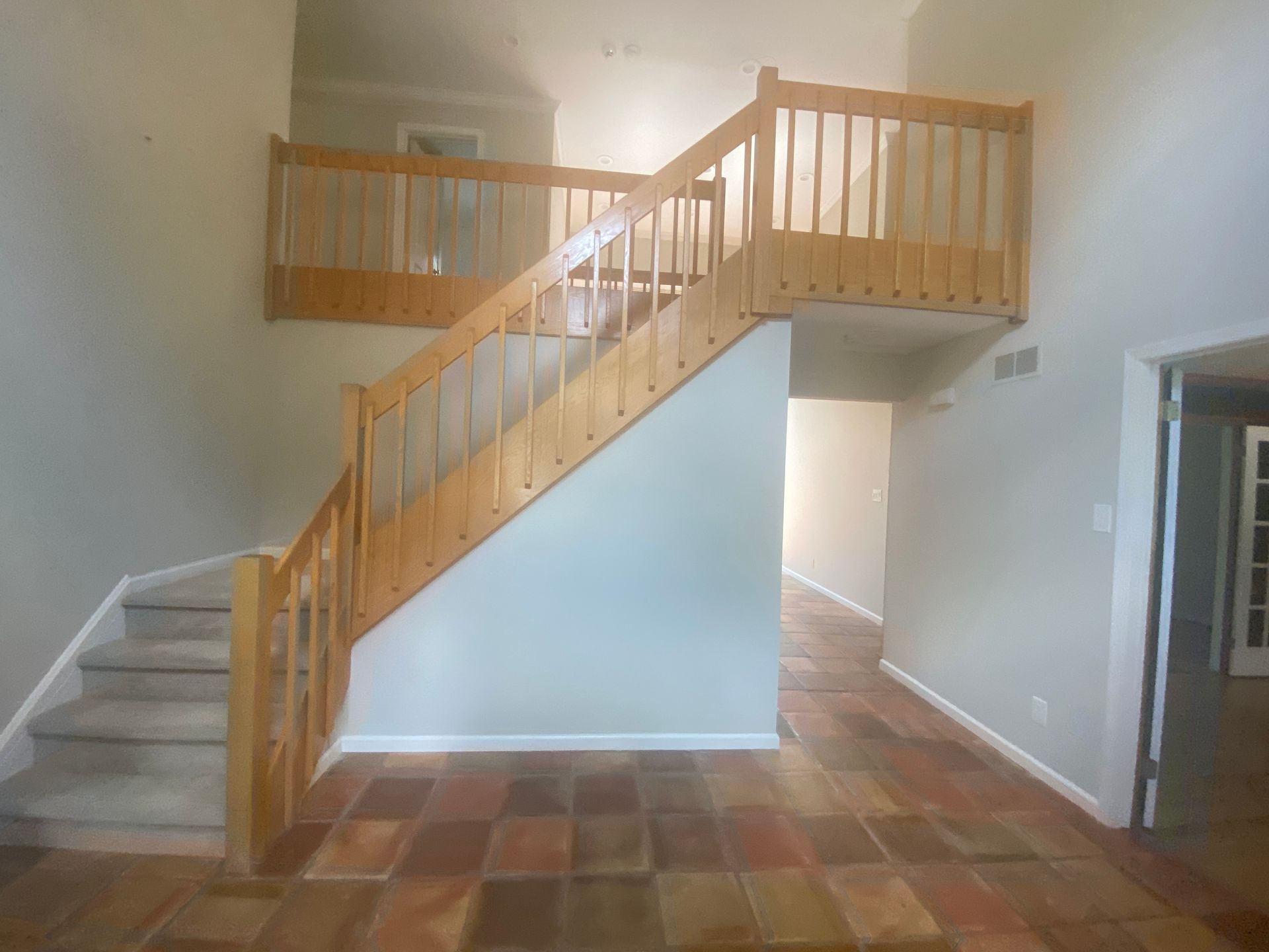 An empty living room with stairs leading up to the second floor.