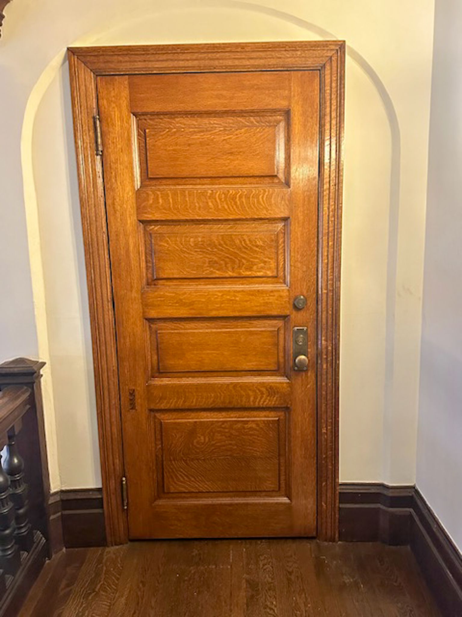 A wooden door is sitting in a hallway next to a wall.