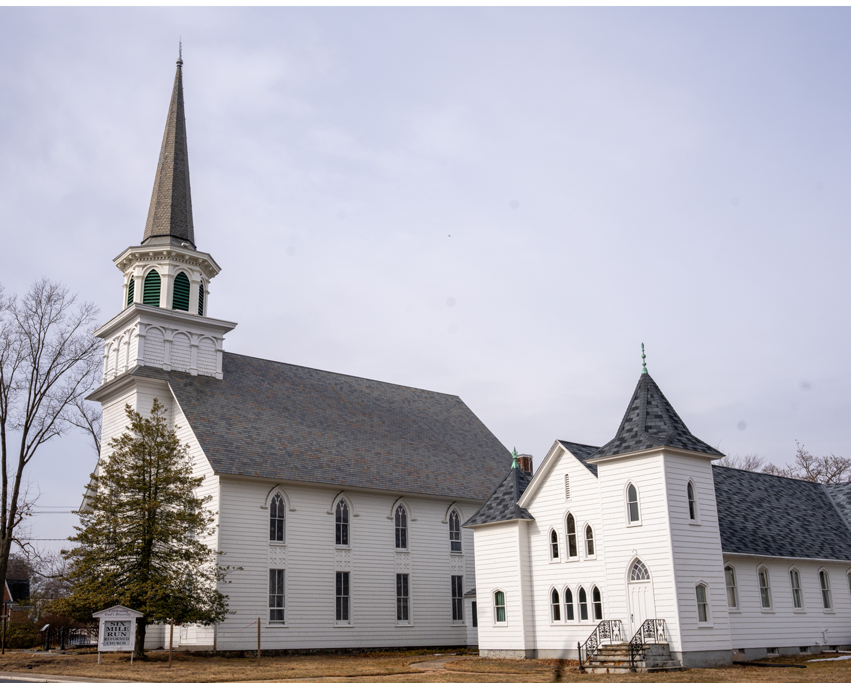 A white church with a steeple and a gray roof