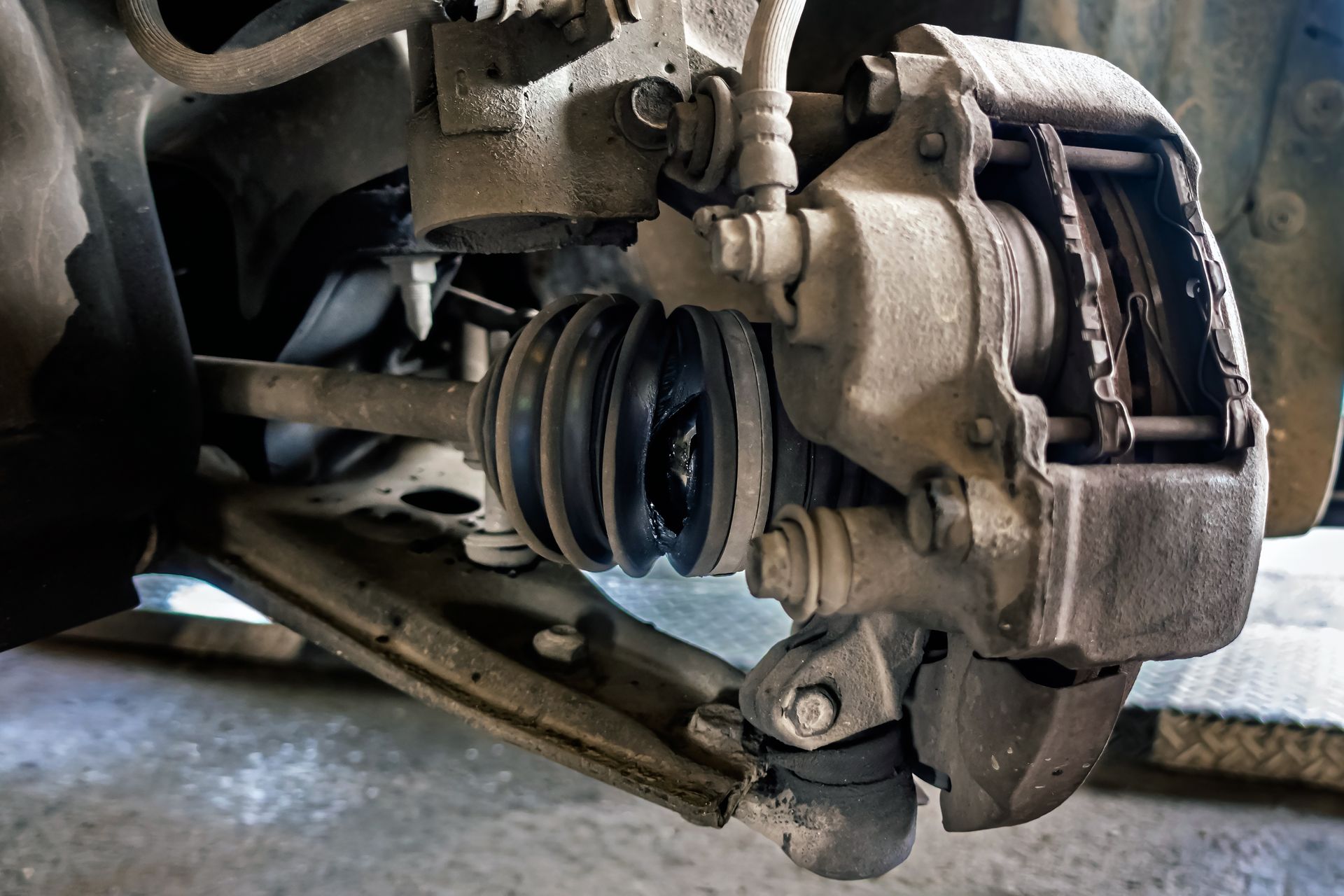 Car's front wheel suspension system with a brake caliper and axle visible.