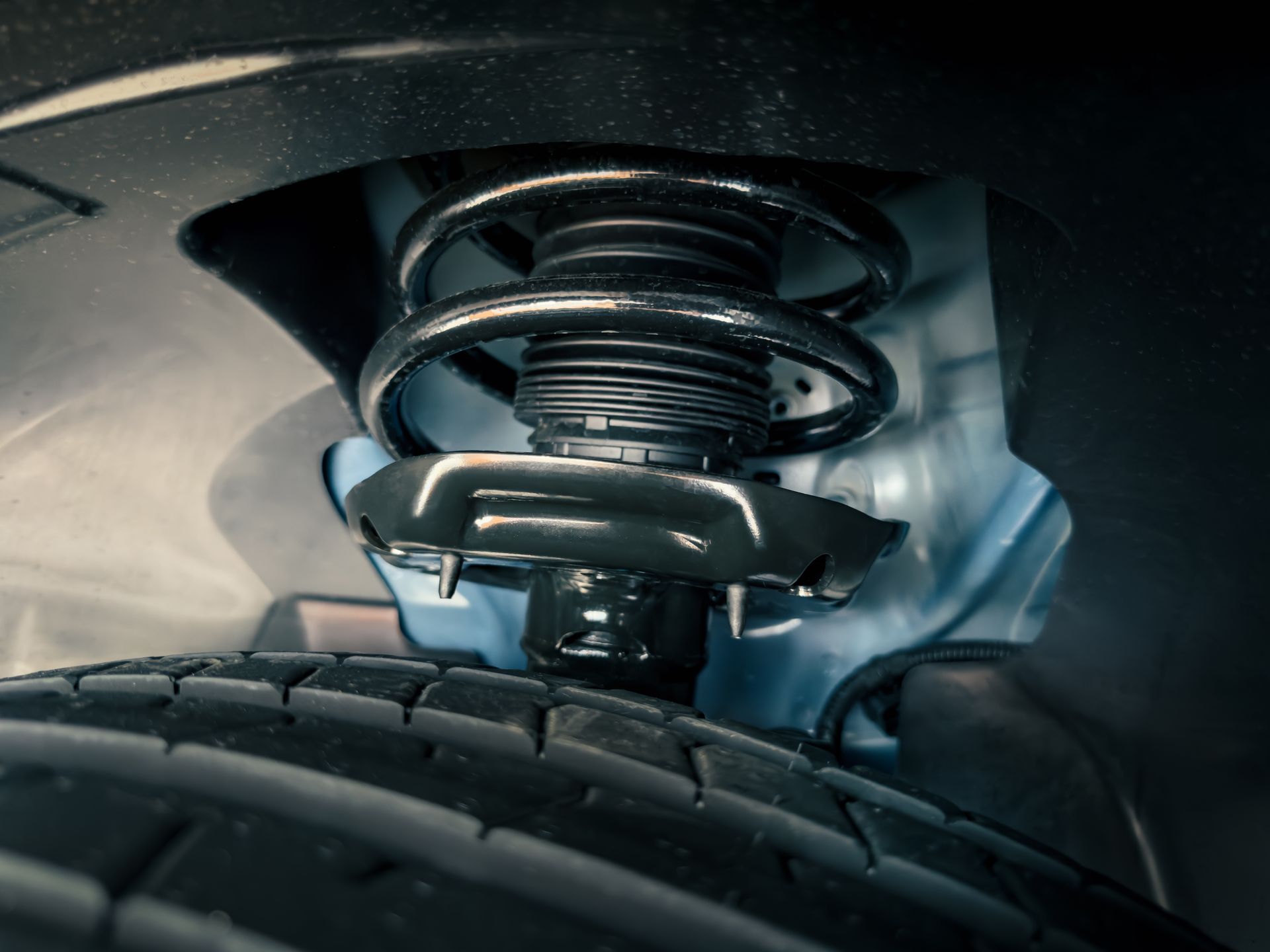 Car suspension system with spring and tire. Black, gray, and blue.