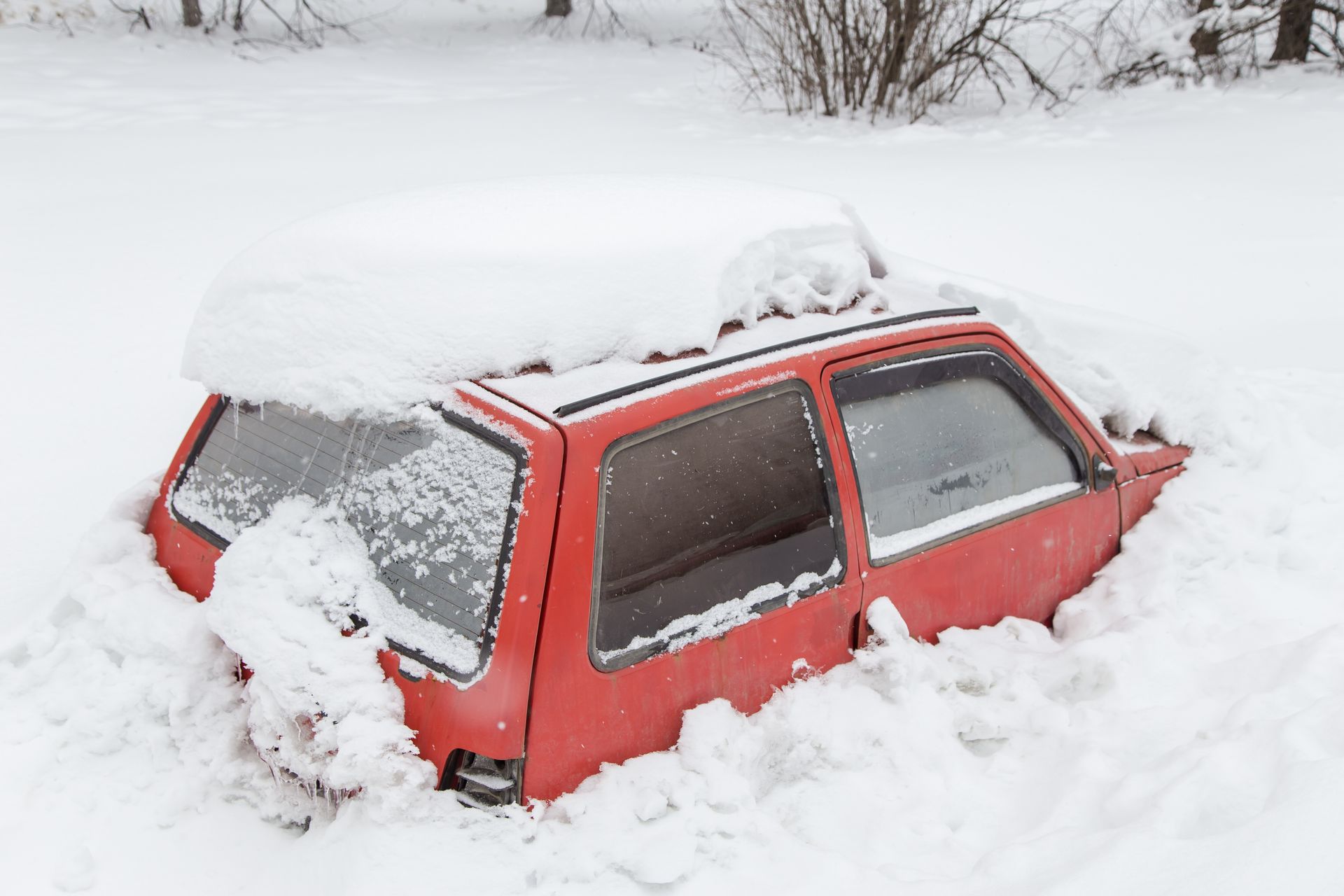 Red car buried in deep snow.