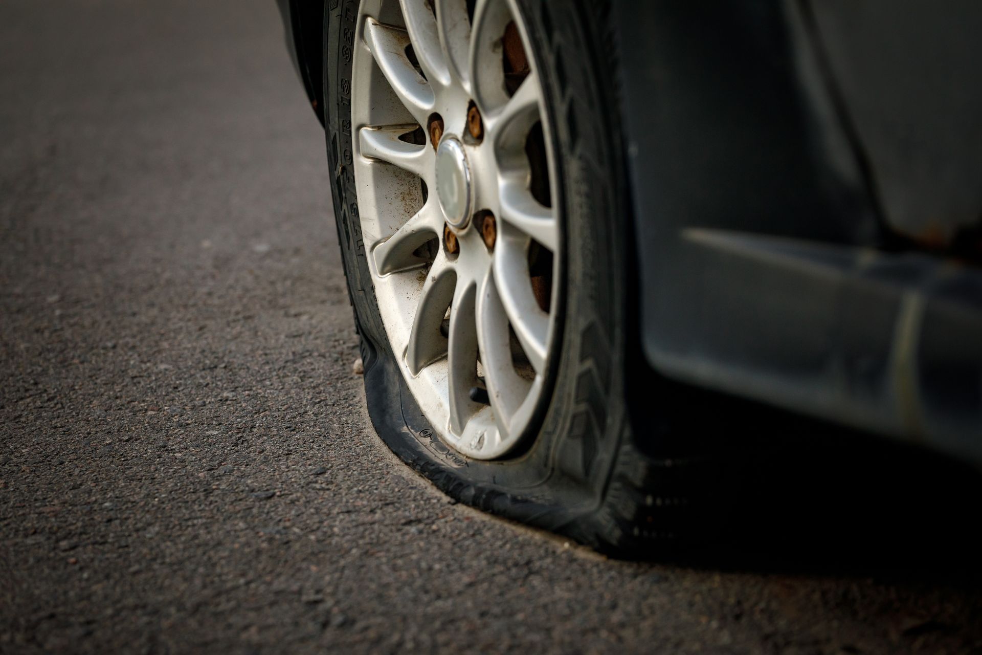 Flat tire on a car parked on asphalt, close-up of damaged wheel