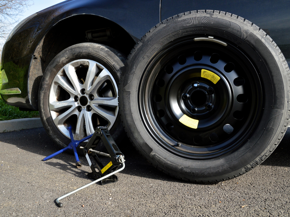 A car with a spare tire and a jack next to it.