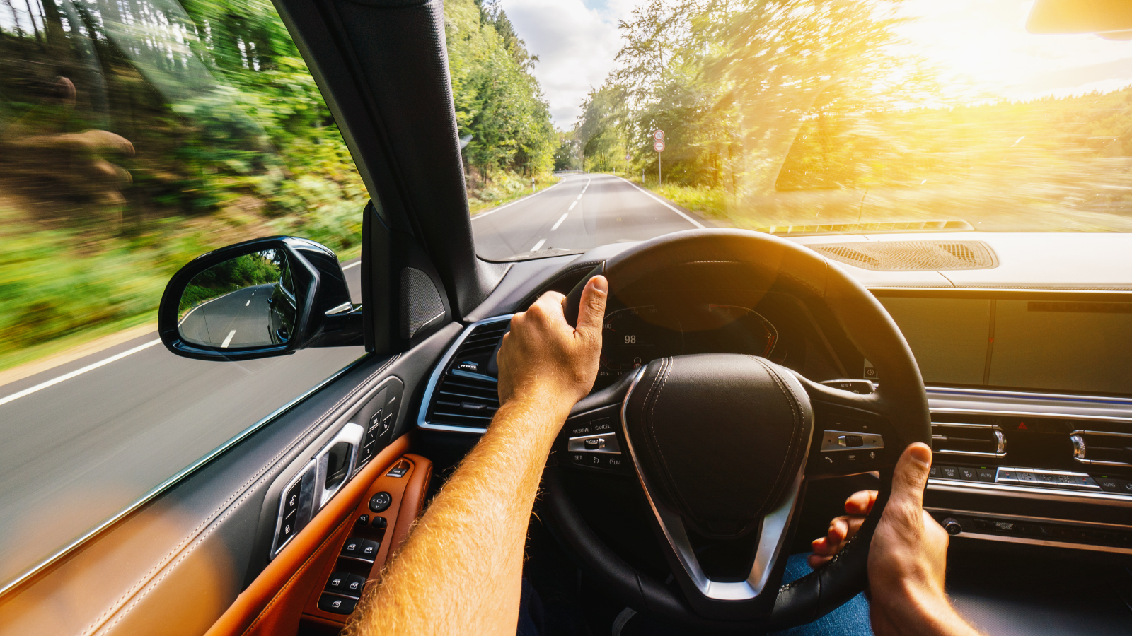 A man is driving a car down a road in the Poconos