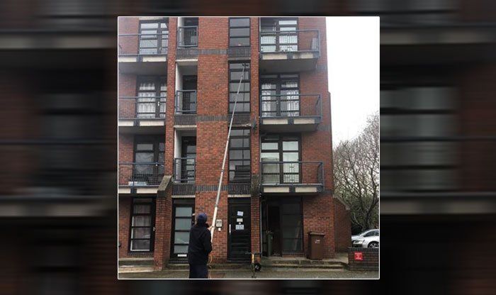 man cleaning window with a long reach and wash pole