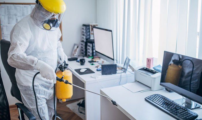 man in a hazmat suit cleaning an office