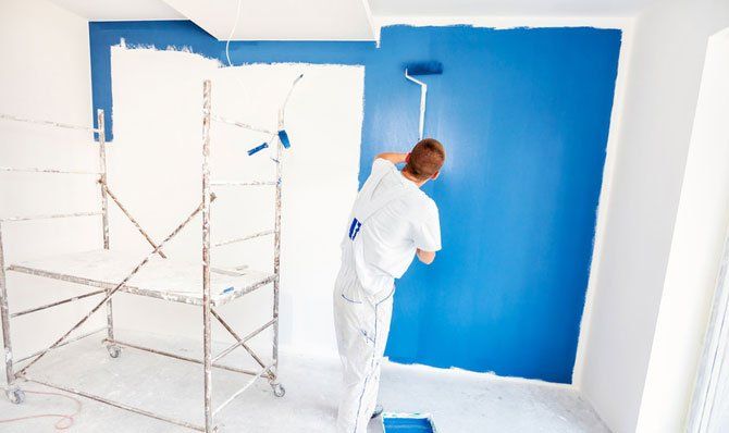 man painting walls with a paint roller