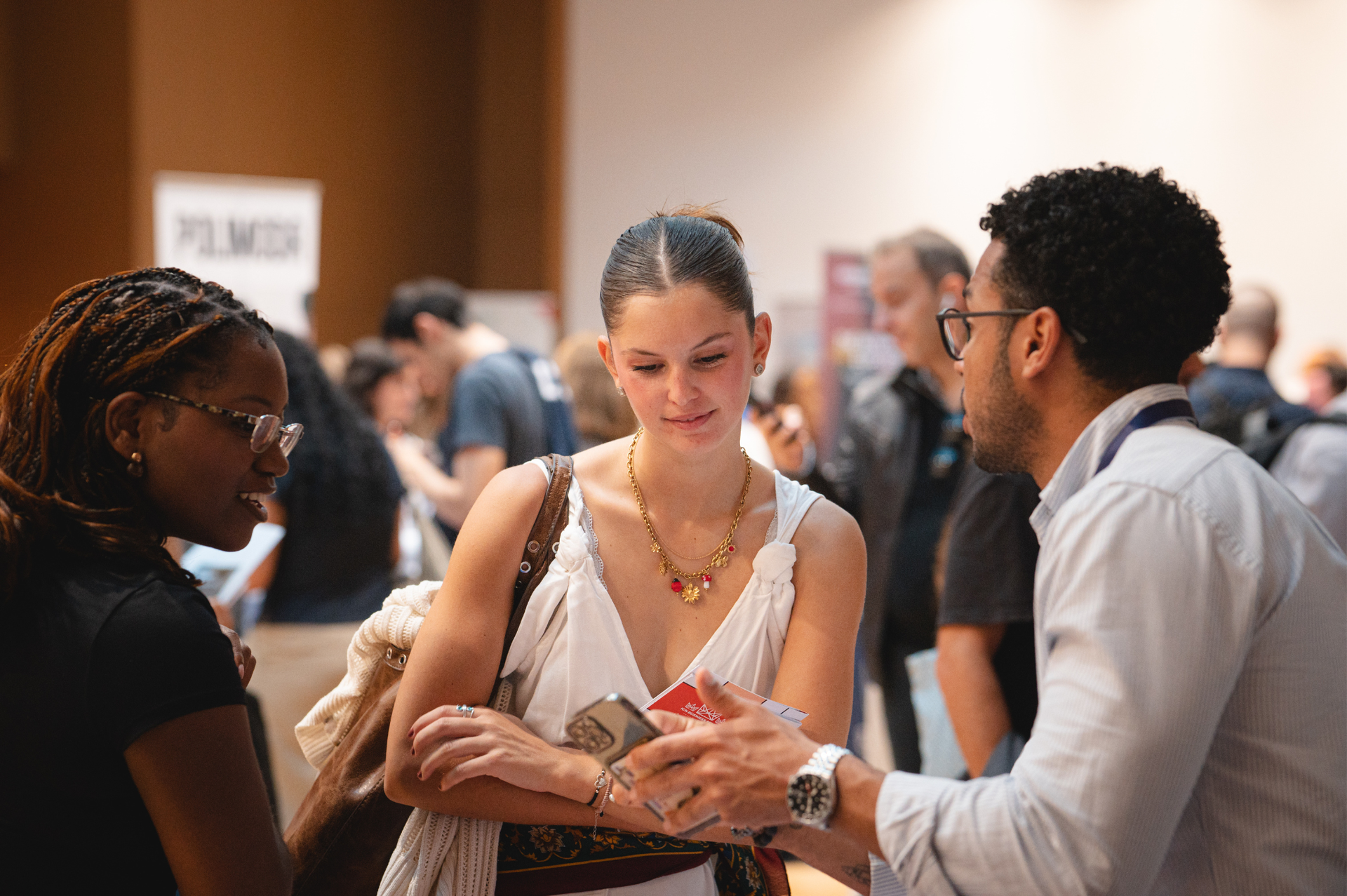 Trzy osoby rozmawiają w pomieszczeniu, dwie kobiety i mężczyzna. Mężczyzna gestykuluje, podczas gdy kobiety słuchają.