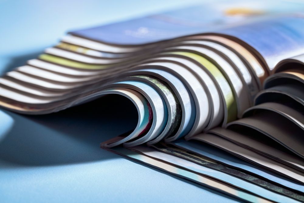 A close up of a stack of magazines on a blue surface.