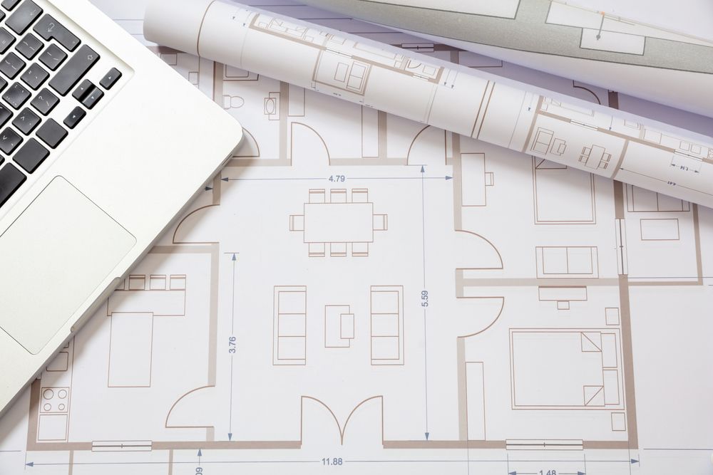 A laptop computer is sitting on top of a floor plan.