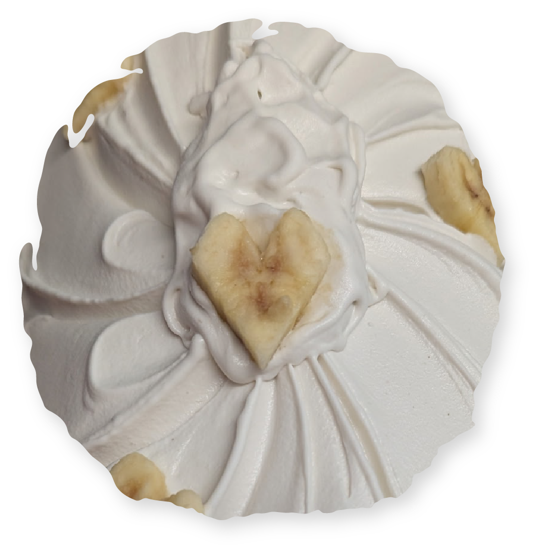 Cupcake topped with white frosting, banana heart, and slices.