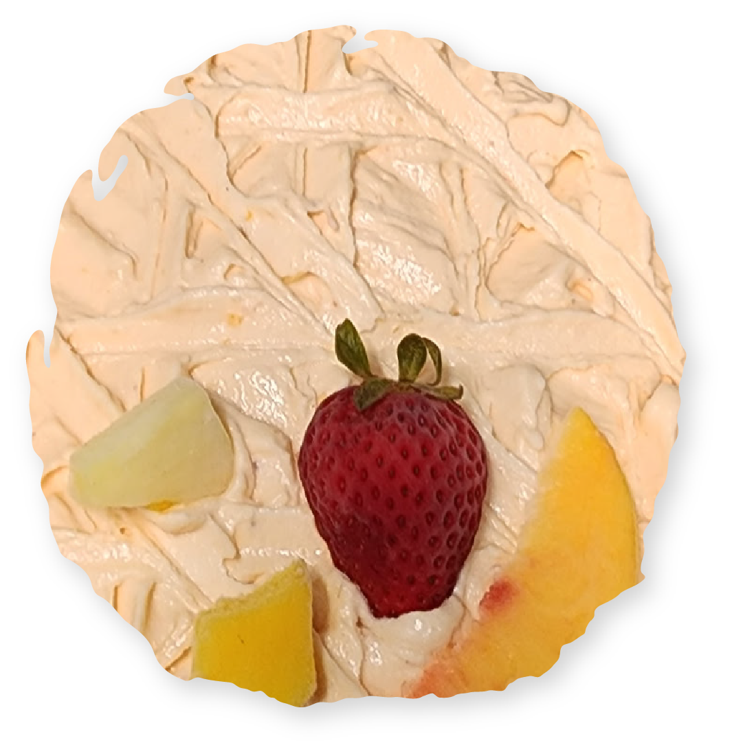A round cake topped with peach-colored frosting, a strawberry, and pieces of fruit.