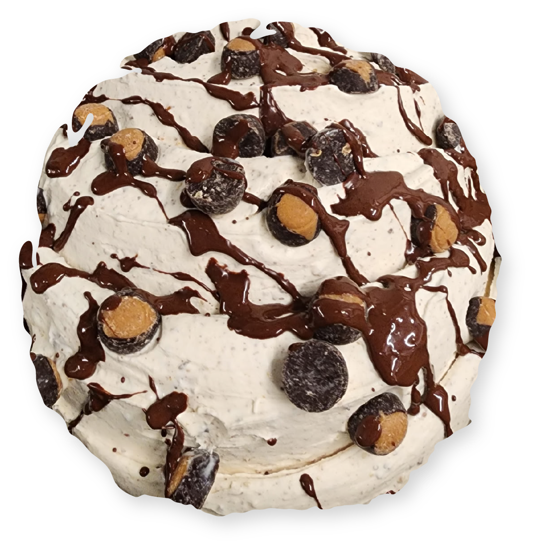 A round dessert, white whipped cream, chocolate drizzle, peanut butter cups and chocolate candies.