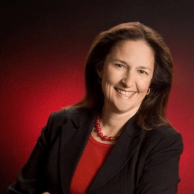 A woman wearing a red shirt and a black jacket smiles for the camera