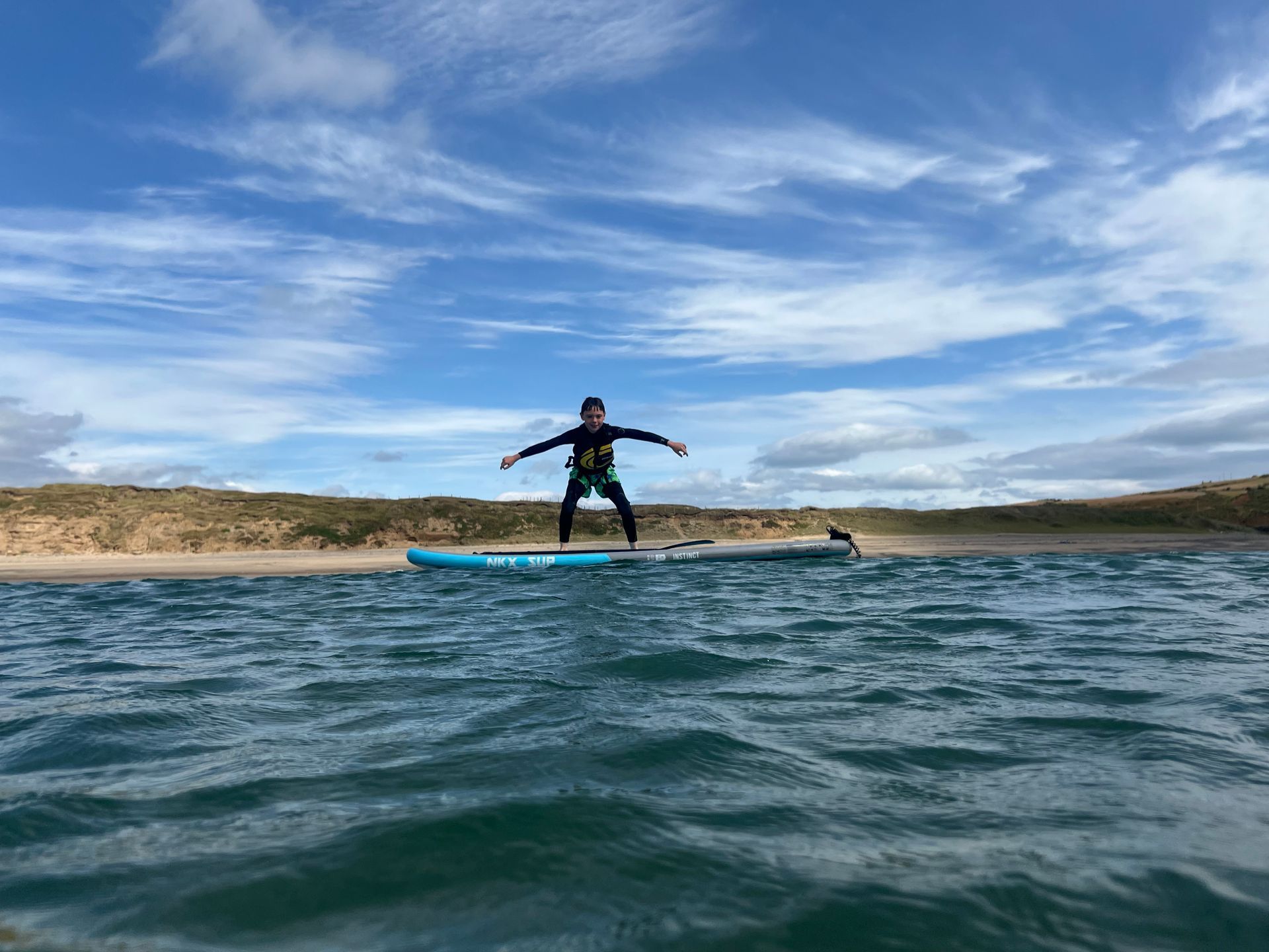 A child in a wetsuit balancing on a paddle-board. Activities available with Northwest Child Care.