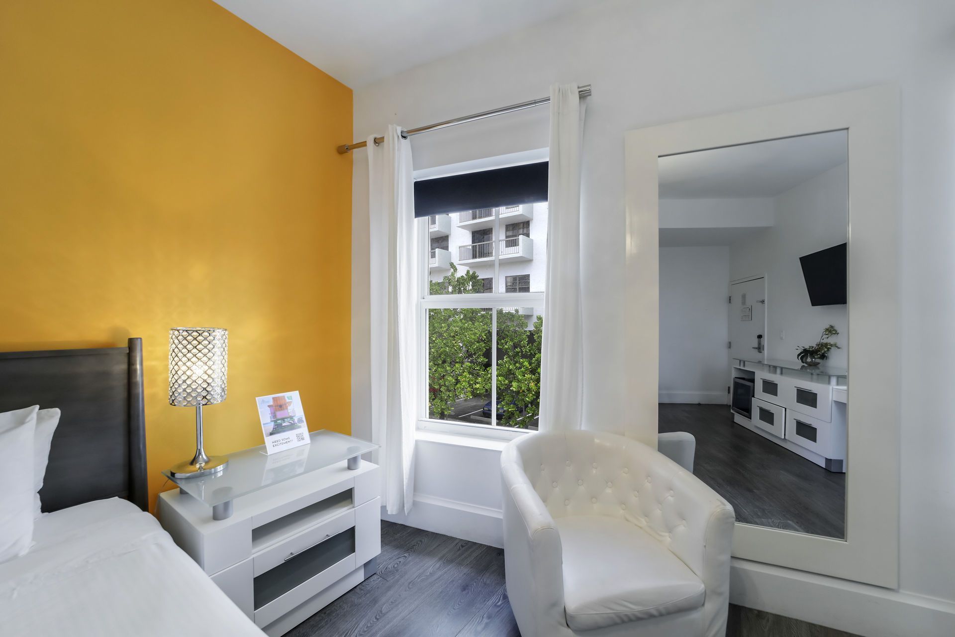 Bedroom with yellow accent wall, white furniture, a window, and a large mirror.