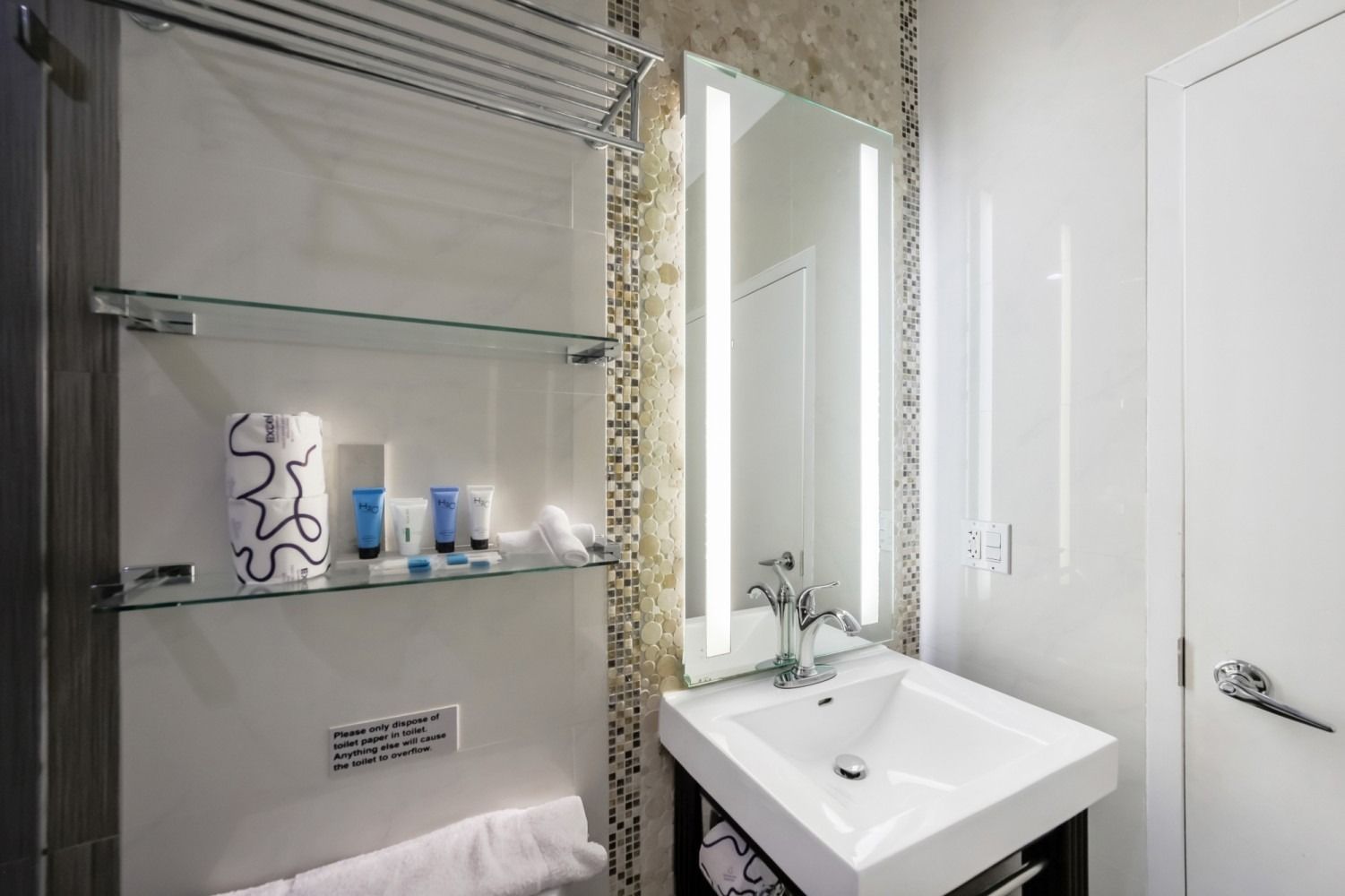 Compact modern bathroom with shower shelves, sink, mirror, and white walls.
