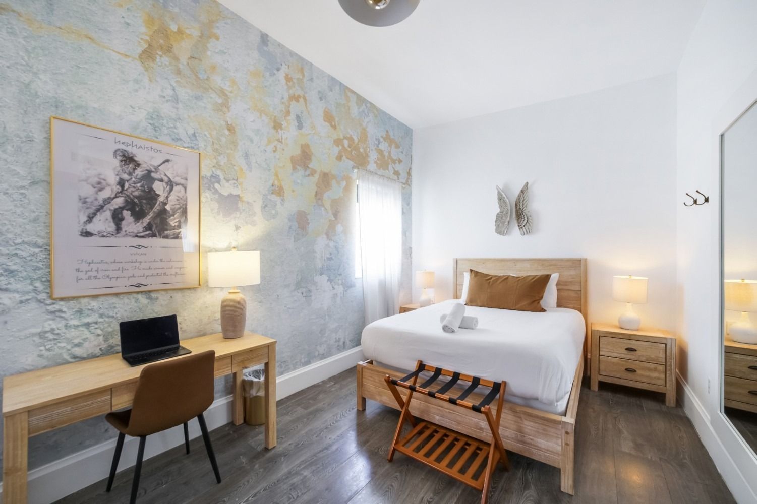 Bright bedroom with a large bed, desk, bedside lamps, and pale blue floral wallpaper