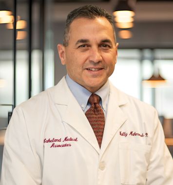 Smiling doctor in a white coat standing indoors with a blurred office background