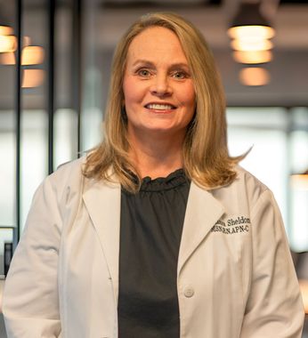 Smiling woman in a white lab coat standing in a modern office lobby