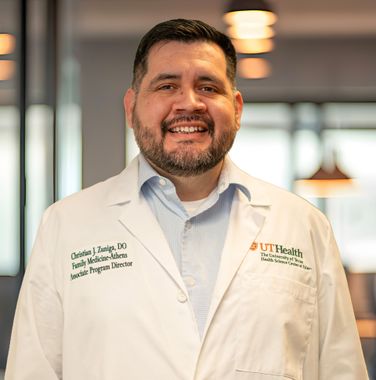 Smiling doctor in a white coat standing in a bright clinic hallway