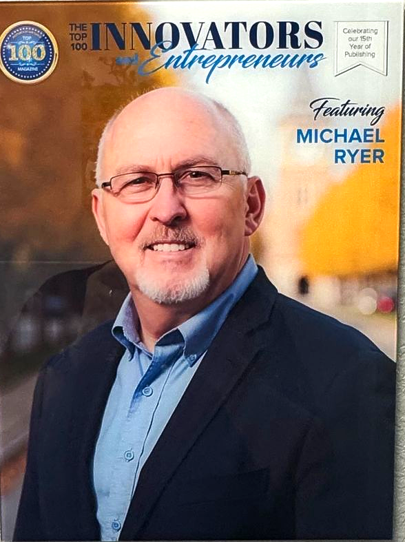 Magazine cover with Michael Ryer. He is wearing glasses, a blue shirt, and a dark blazer. The cover says