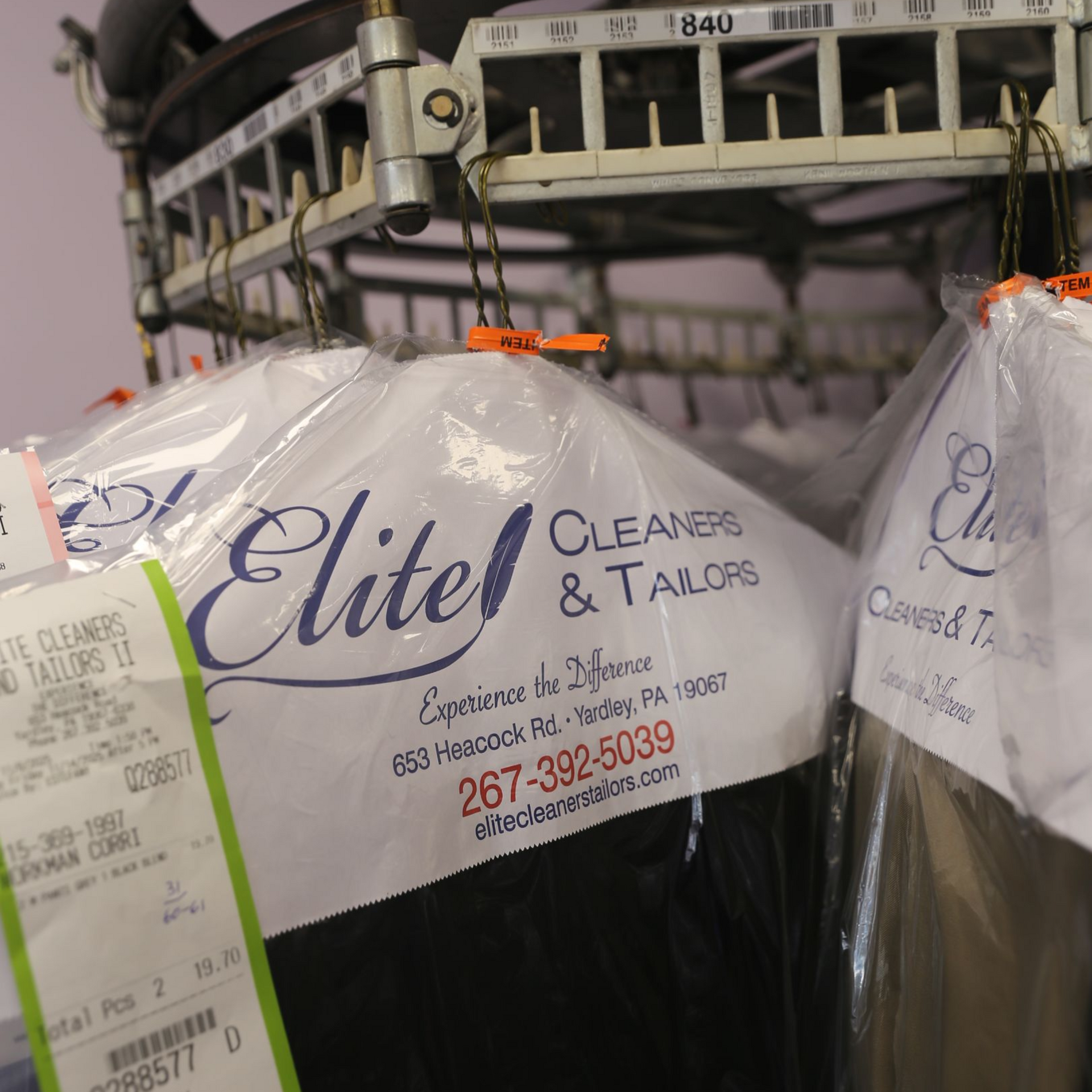 Dry-cleaned clothes in plastic bags hanging on a rack at Elite Cleaners & Tailors in Yardley, PA.