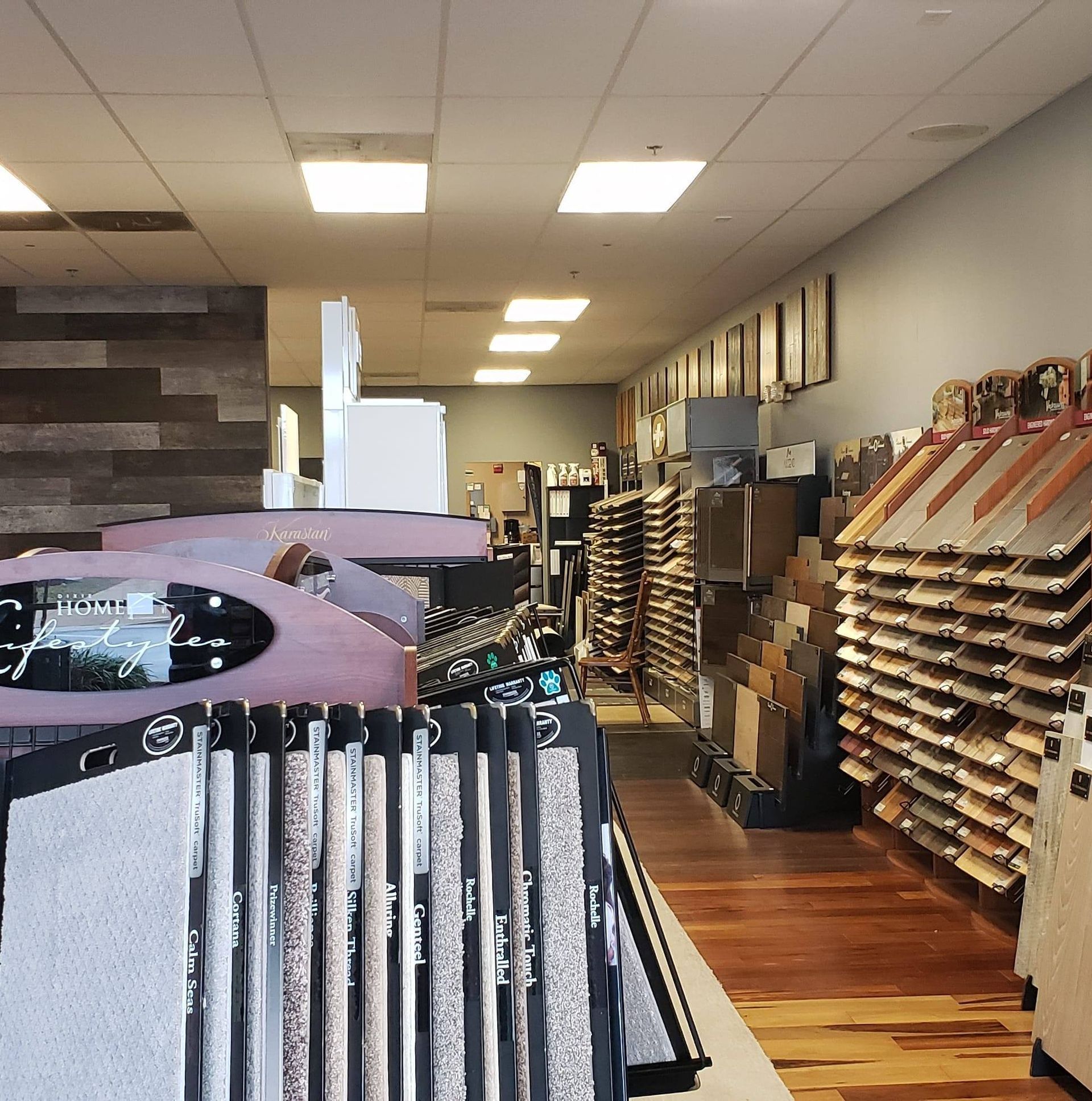 Interior view of a flooring store displaying various samples of carpet, tile, and wood.