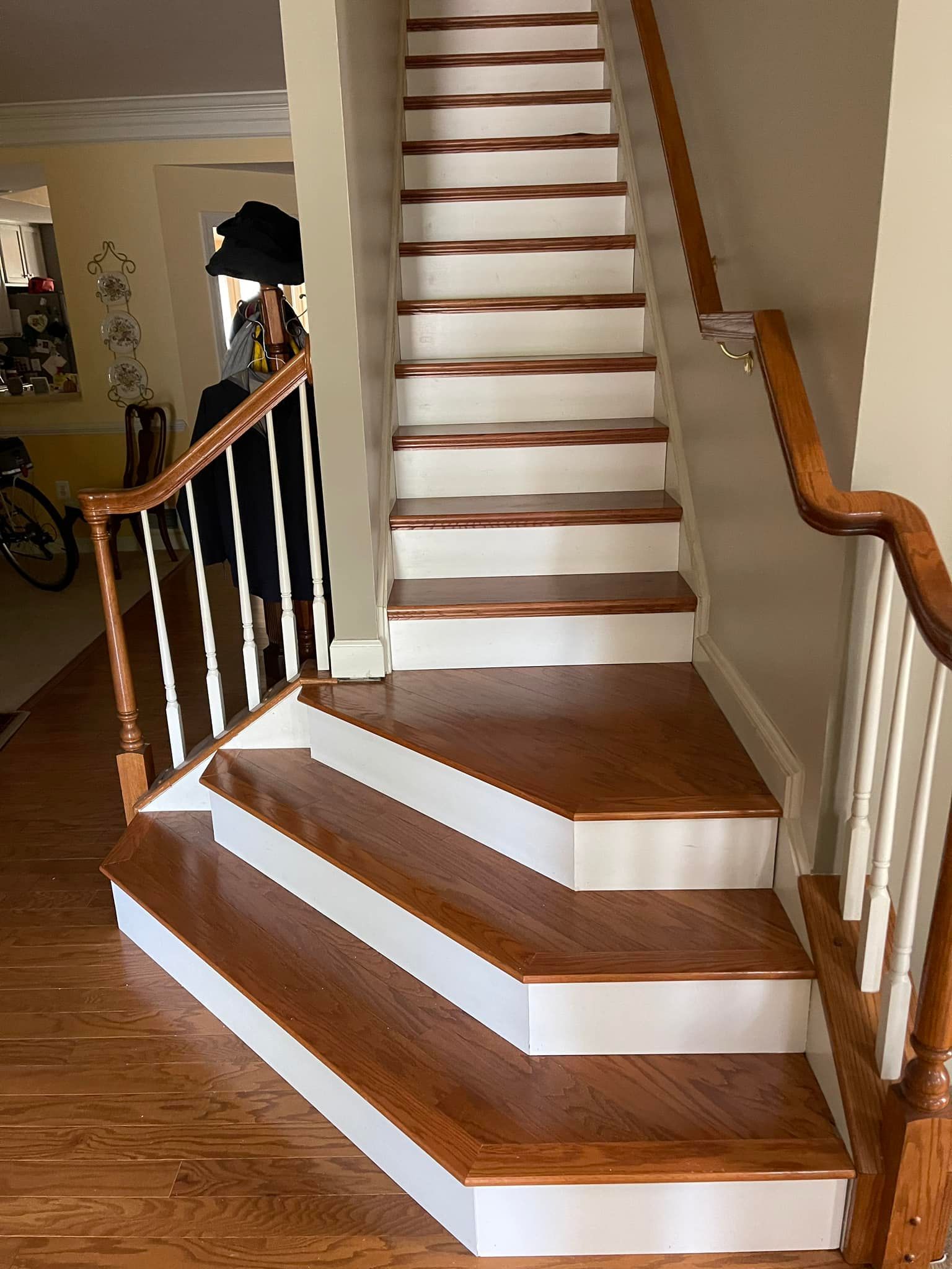 Wooden staircase with white risers, brown treads, and a person standing on the landing.