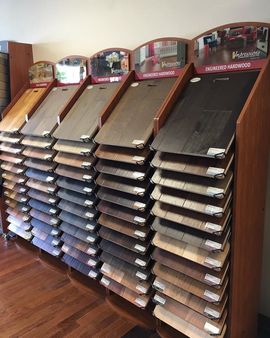 Flooring samples displayed on a wooden rack, showcasing various wood tones and styles.