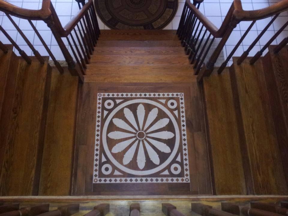 Wooden staircase with decorative floral inlay on landing.