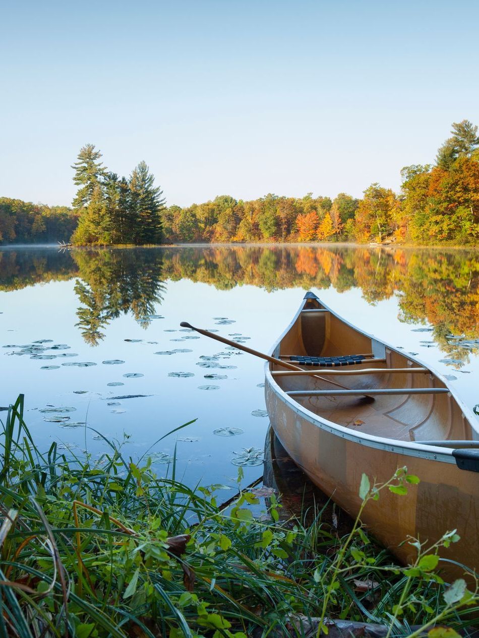 A wooden walkway leading to a gazebo overlooking a body of water at sunset.