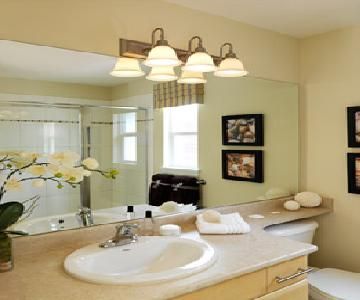 A bathroom with a sink a toilet and a large mirror