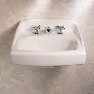 A white bathroom sink with three faucets on a tiled floor.