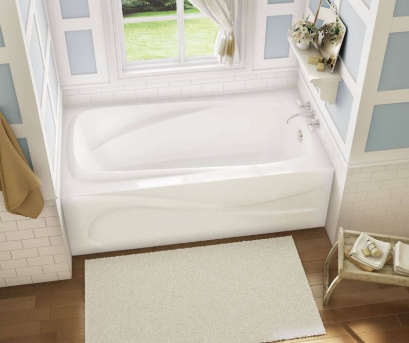 A white bathtub in a bathroom next to a window