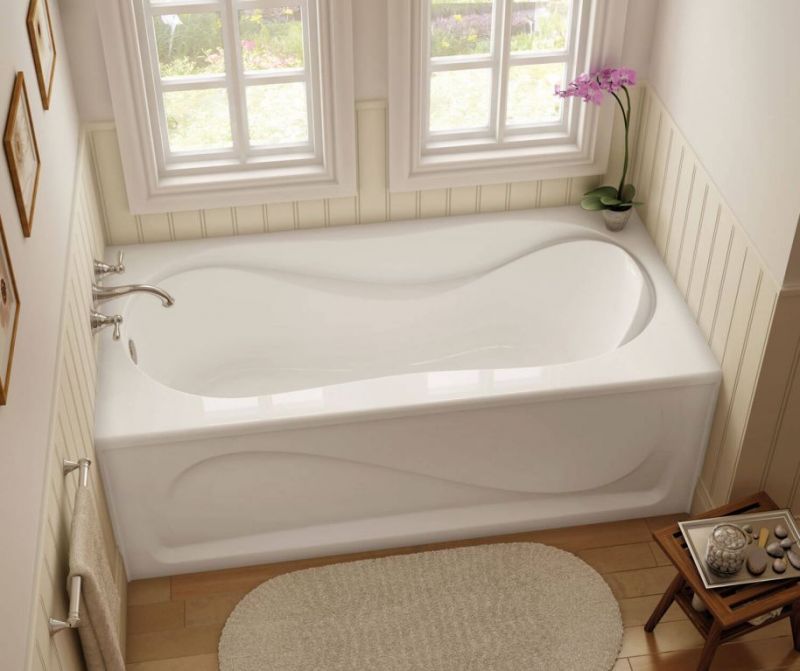 A white bathtub in a bathroom next to a window