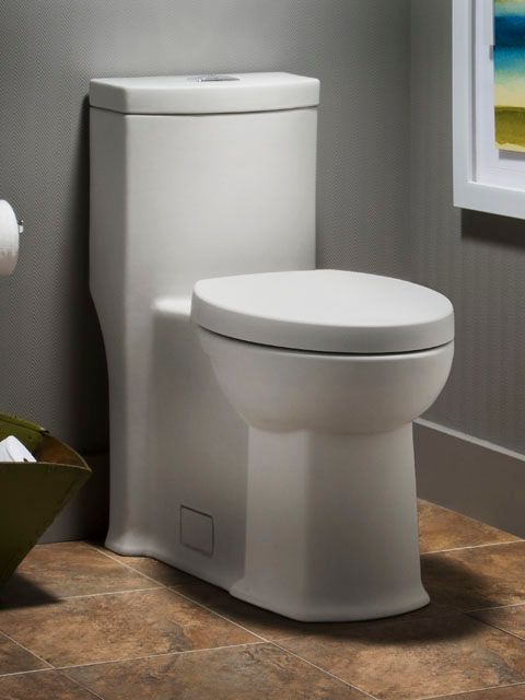 A white toilet in a bathroom next to a basket of toilet paper