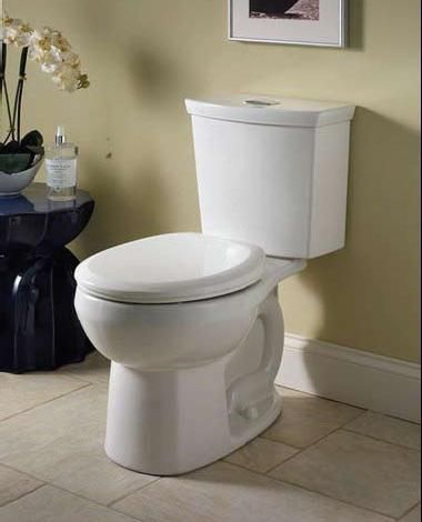 A white toilet is sitting on a tiled floor in a bathroom.