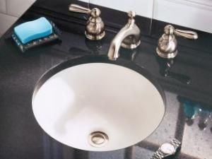 A bathroom sink with a soap dish and a watch on the counter