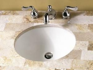 A bathroom sink with three chrome handles on a tiled counter top.
