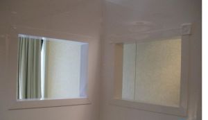 A corner of a room with two mirrors and a window.