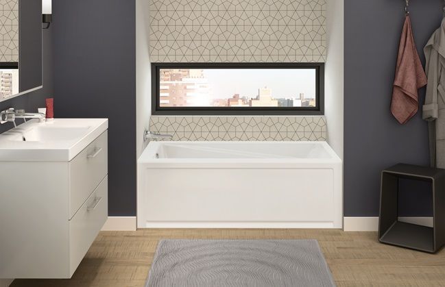 A bathroom with a tub , sink , mirror and window.