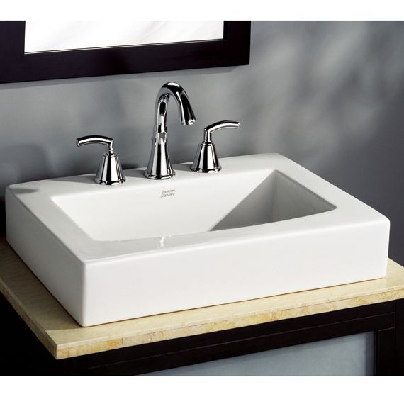 A white sink with chrome handles sits on a counter