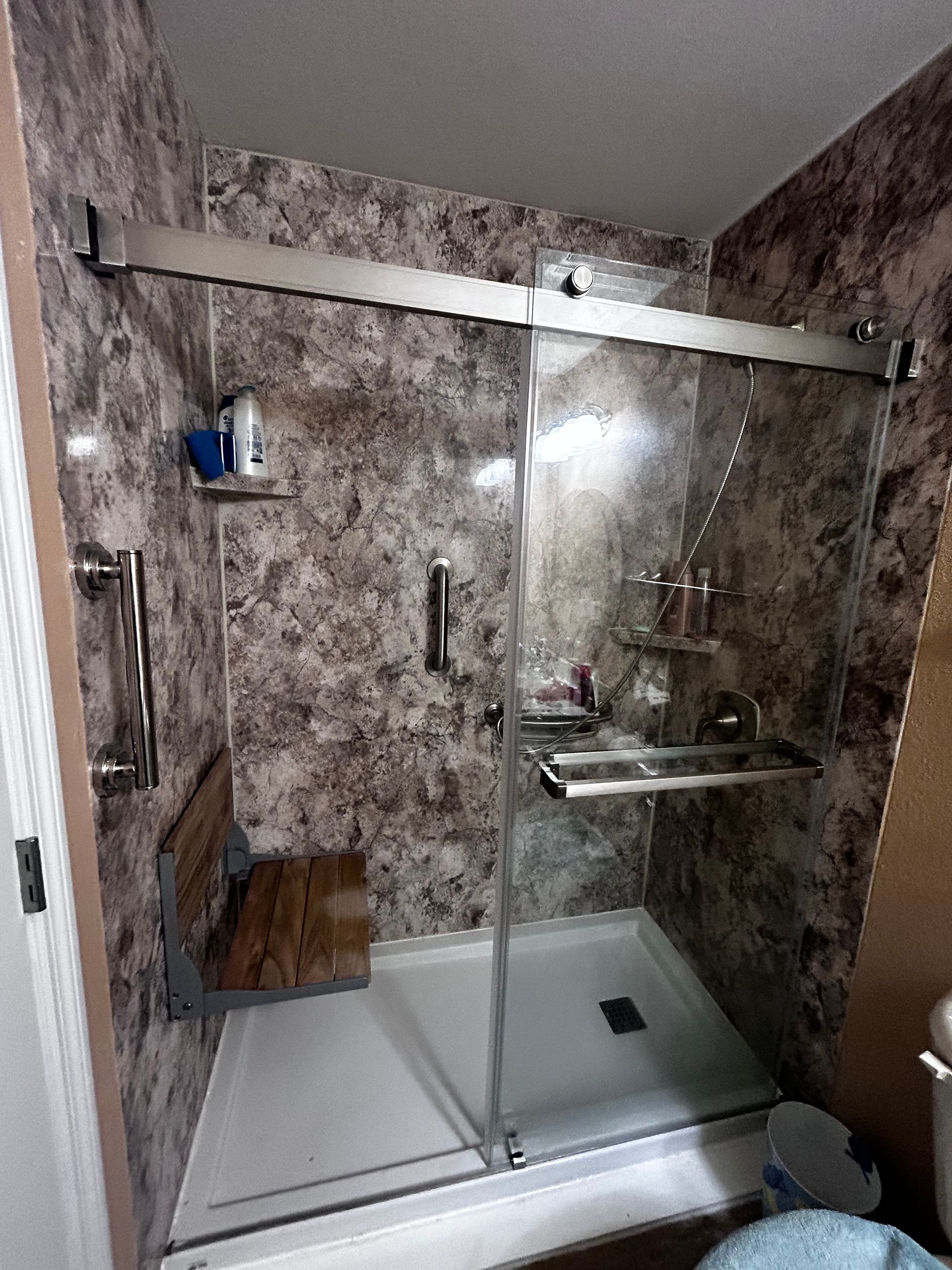 A bathroom with a walk in shower with a sliding glass door.