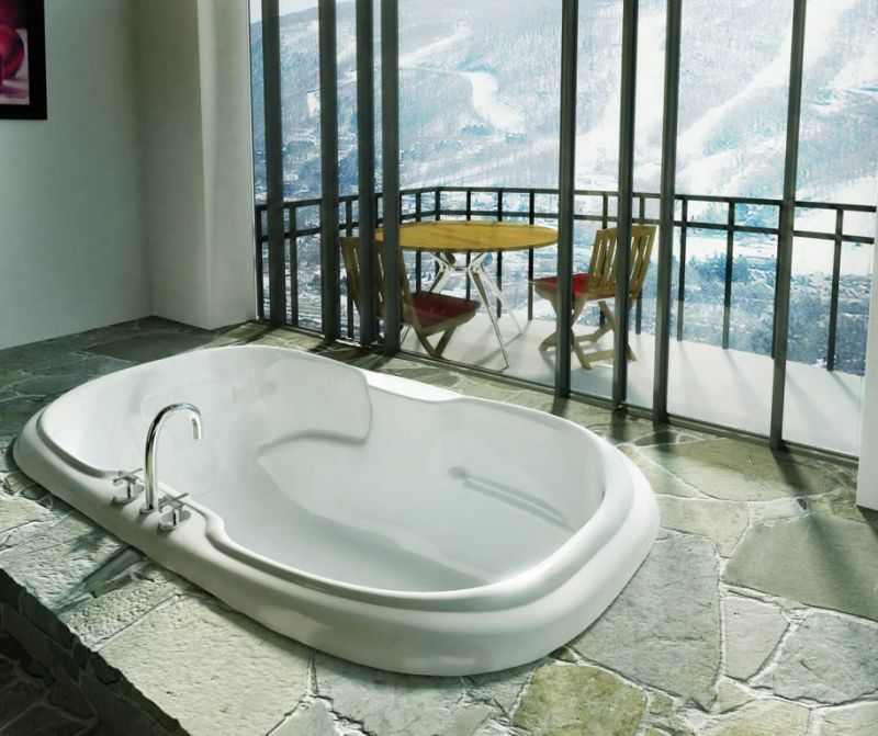 A bathtub in a bathroom with a table and chairs in the background