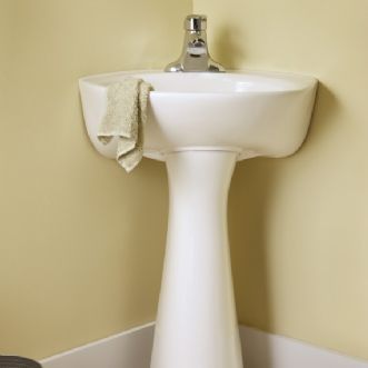 A white pedestal sink in a bathroom with a towel on it.