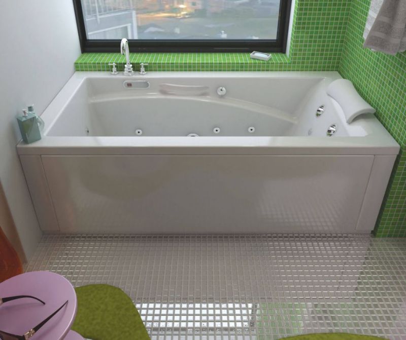 A bathtub in a bathroom with green tiles and a window