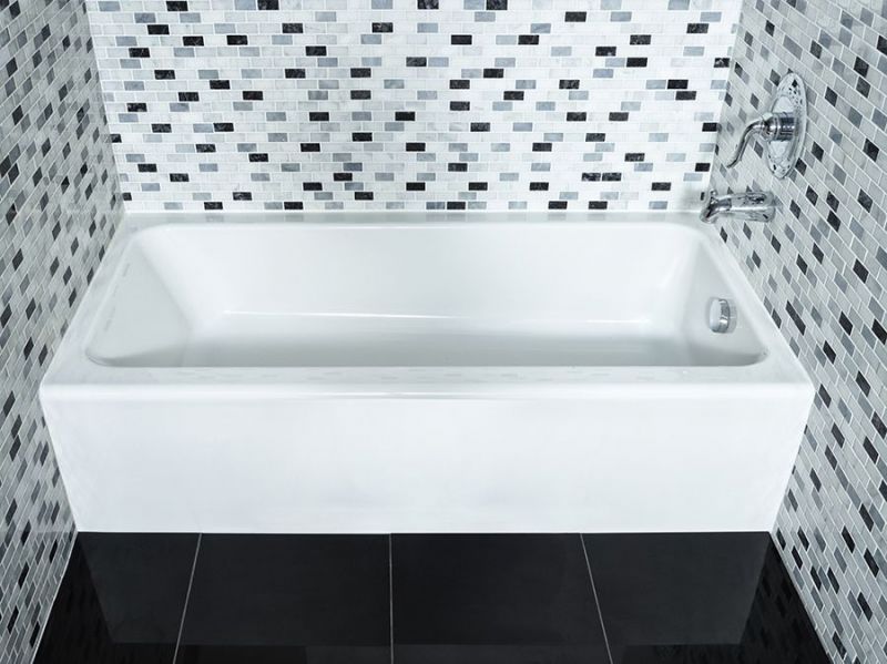 A white bathtub in a bathroom with black and white tiles